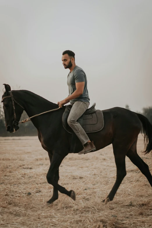 a man in a gray shirt is riding a horse