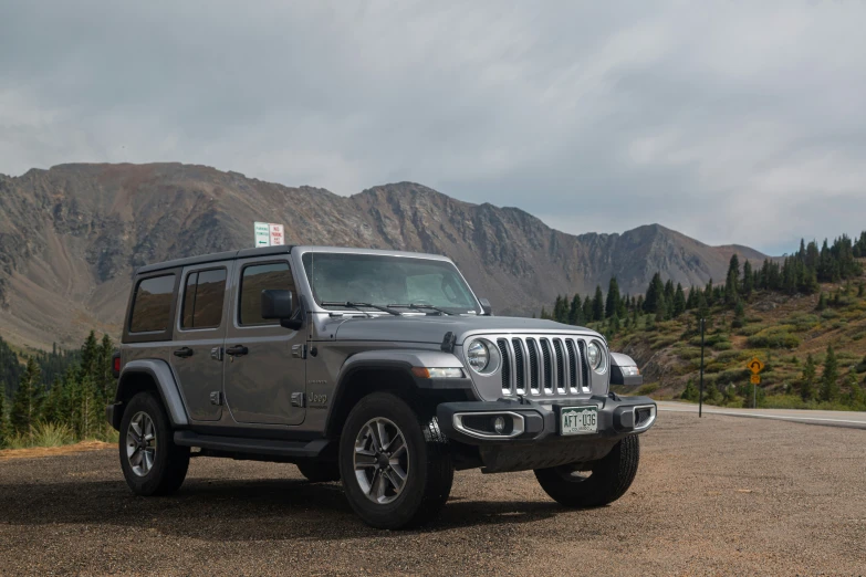 a jeep with a sale sign on top parked next to mountains