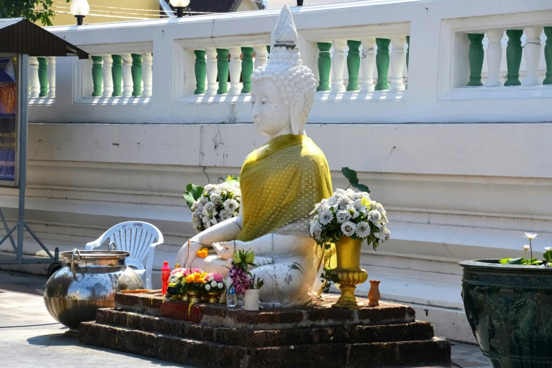 a white statue in front of a wall next to potted flowers