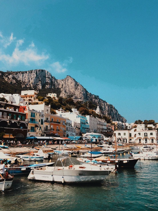 small boats moored at the dock next to buildings on a hill