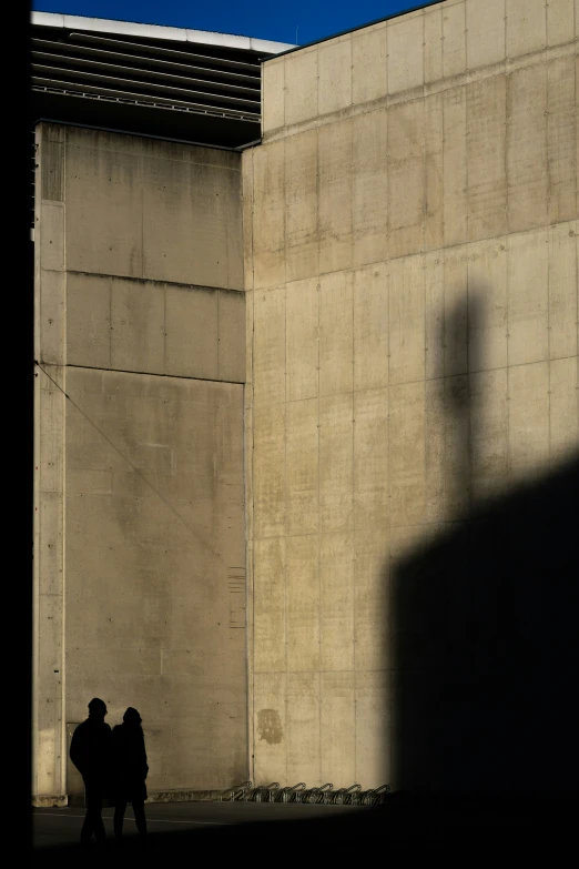 two people walking down a street under an overpass