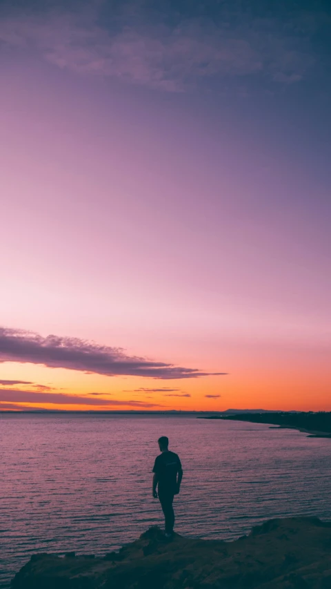 man walking toward the ocean at sunset during the day