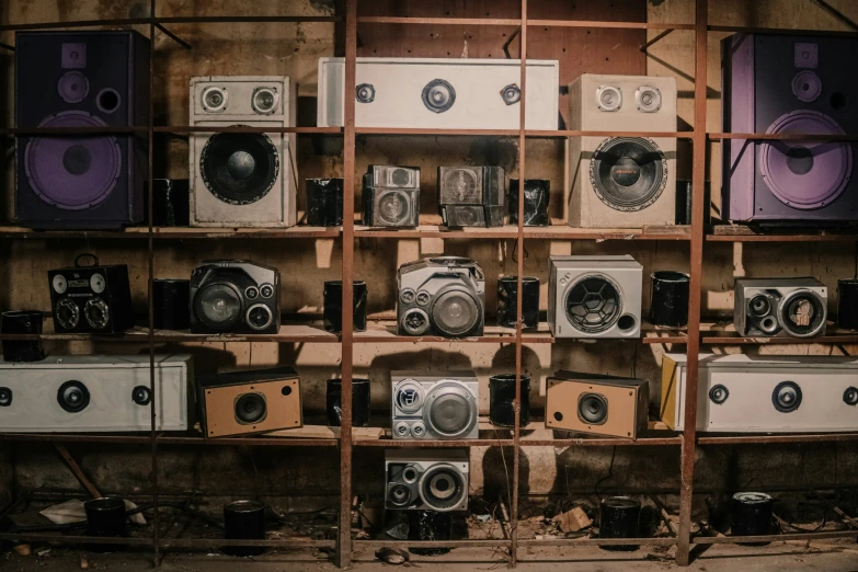 old cameras and speakers are stacked up on a wooden shelving unit