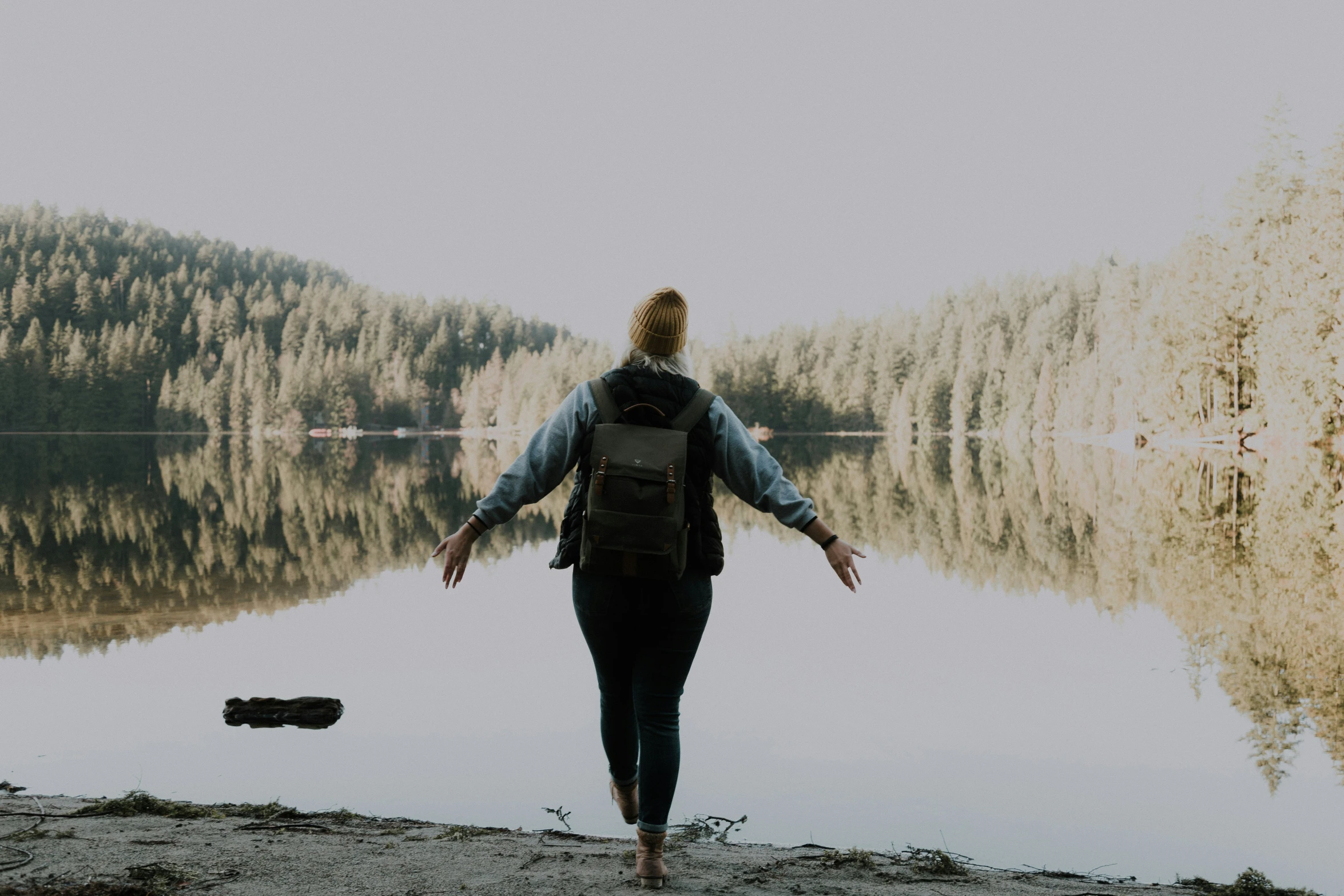 a woman with a backpack walks near a body of water