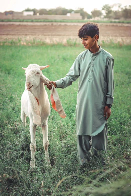 a boy holding an animal in his hand while standing on grass