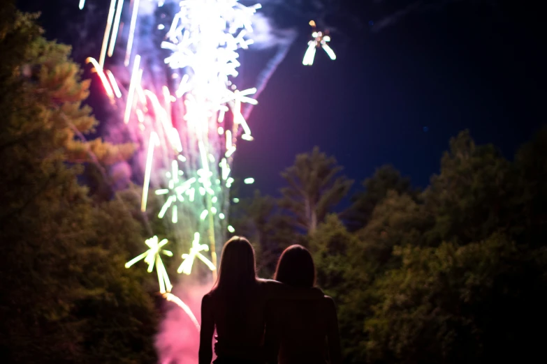 a couple of people looking at fireworks in the sky