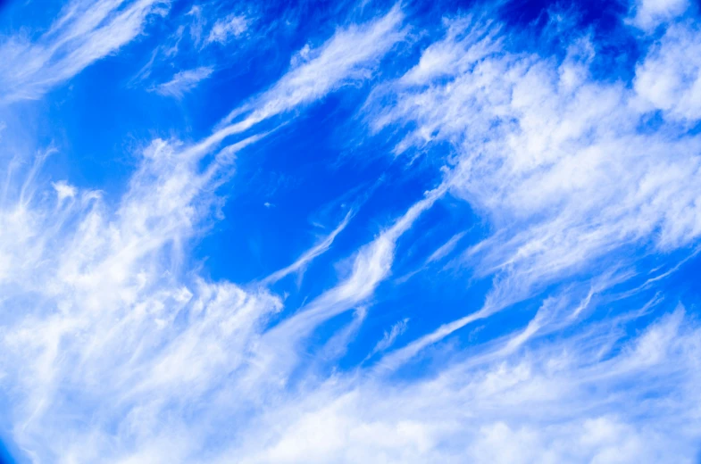 a large blue sky with clouds and a plane flying by