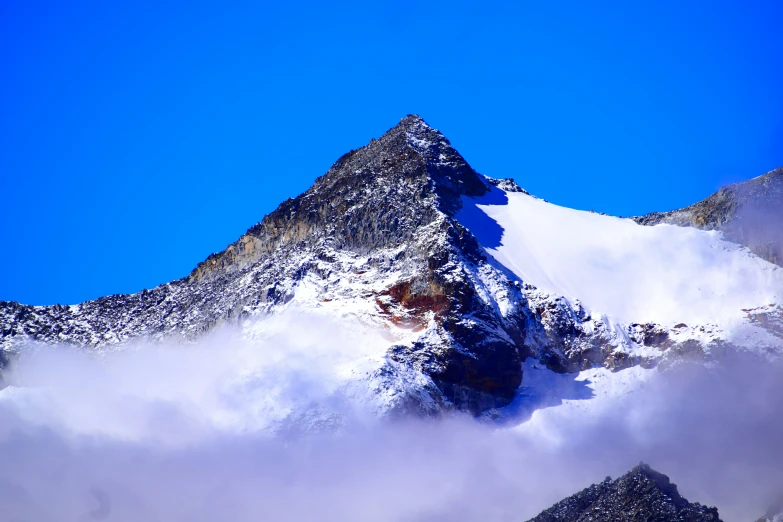 a snowy mountain top rises above the clouds