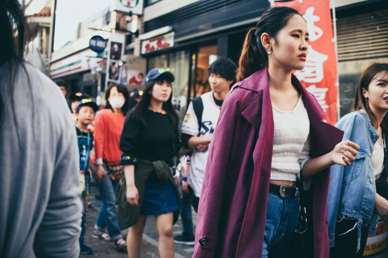 a young woman stands in front of several people walking in a crowded city street