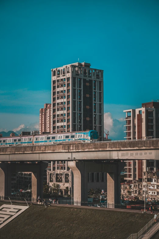 train on elevated track over roadway with city skyline in background