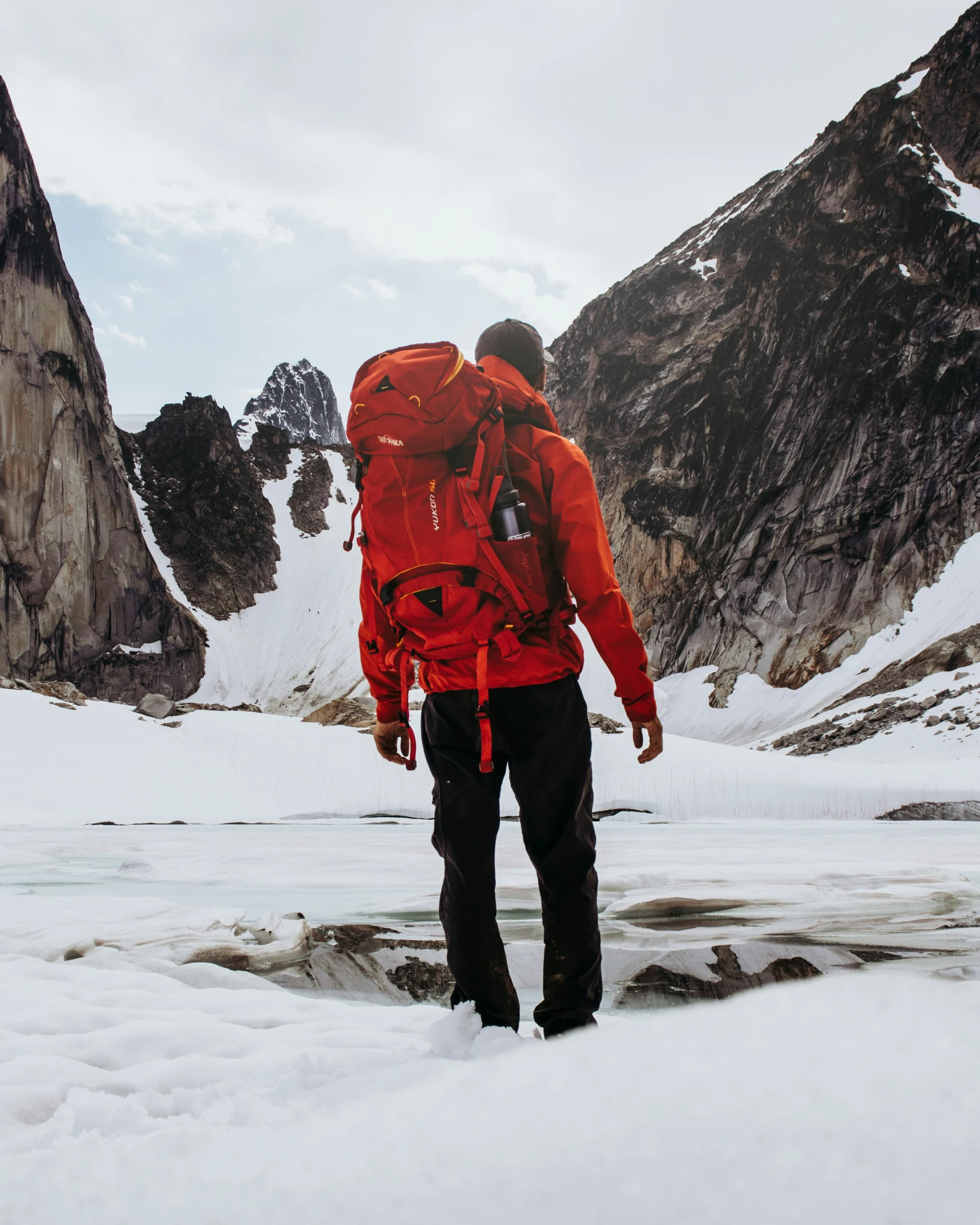 a hiker wearing a red backpack standing on the snow