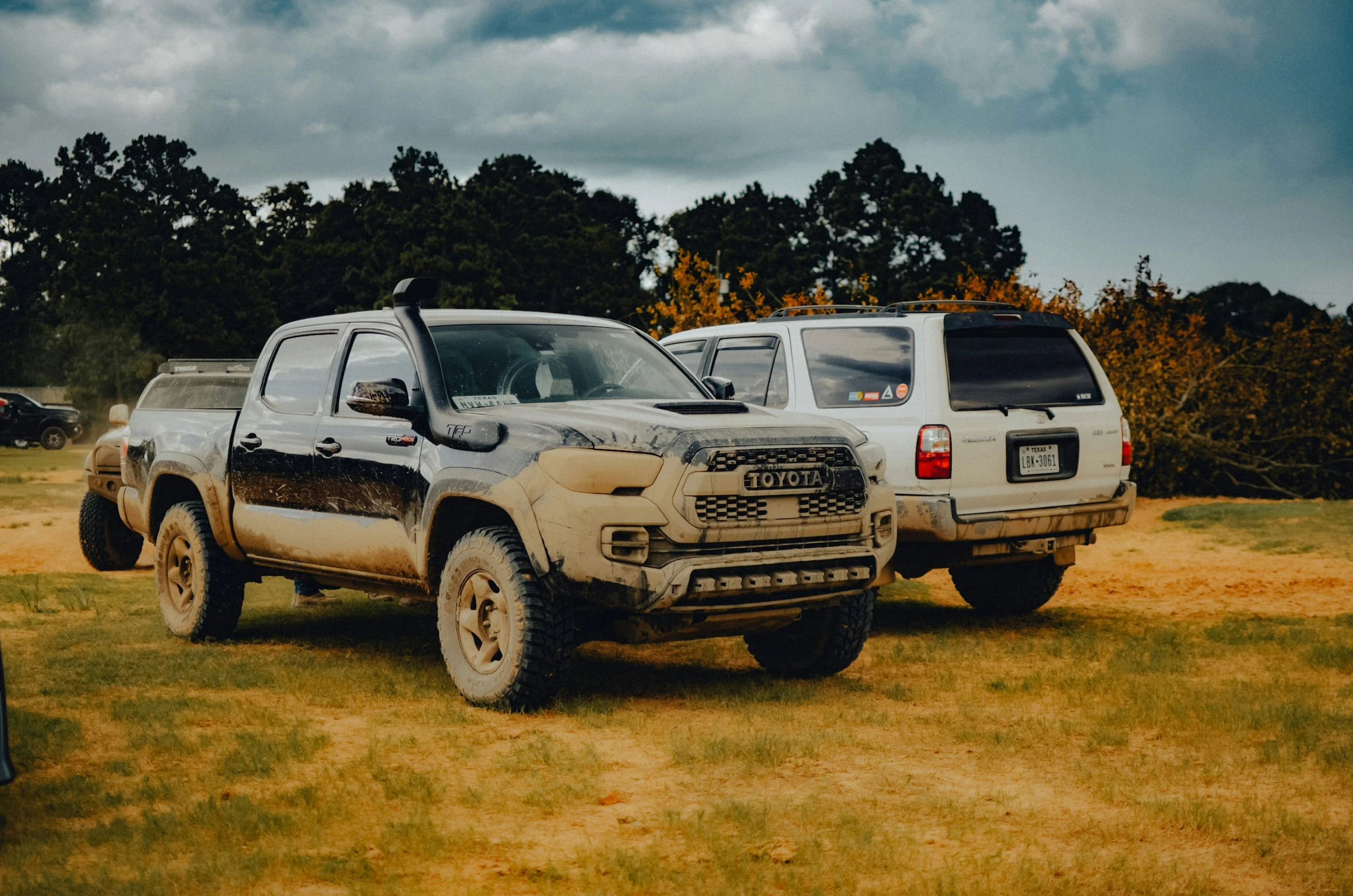 two large trucks are parked on some grass