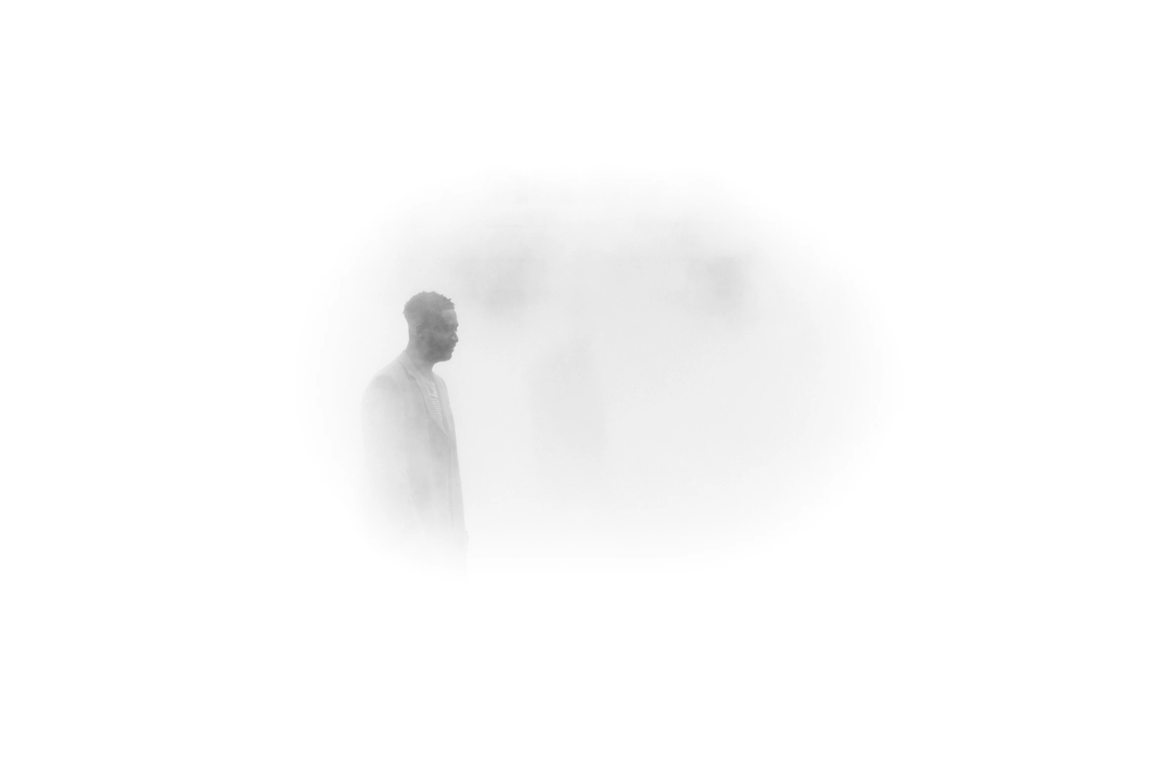 a silhouette of a man standing in the fog with a cellphone