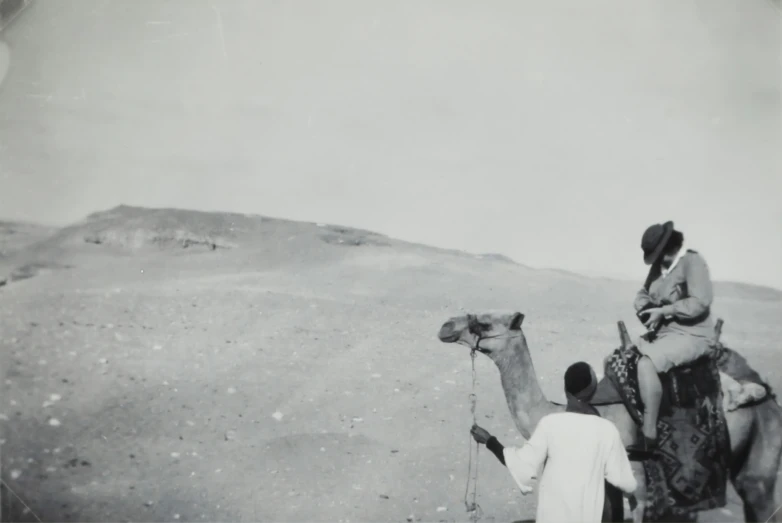 two men are watching a woman on a camel