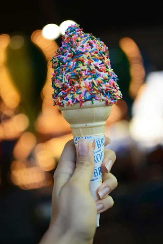 a person is holding an ice cream cone covered with sprinkles