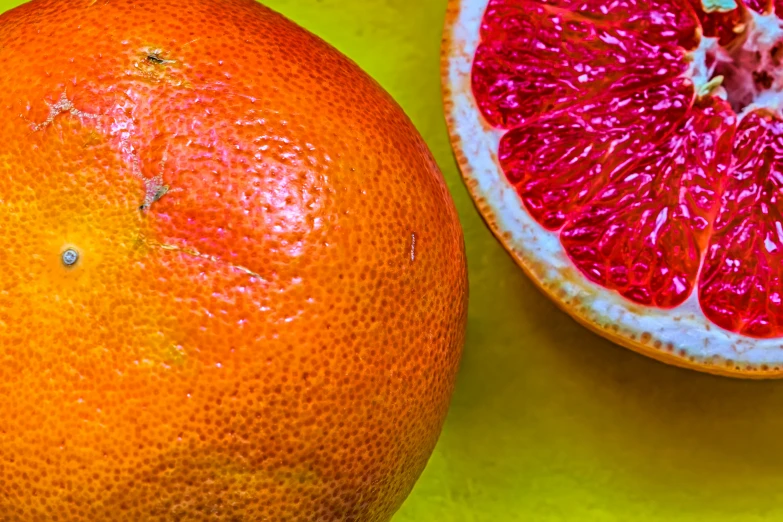 a gfruit and a gfruit sliced up in half on a green table