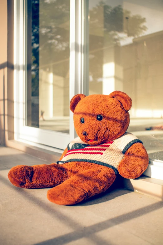 a teddy bear sits on the floor outside of a building