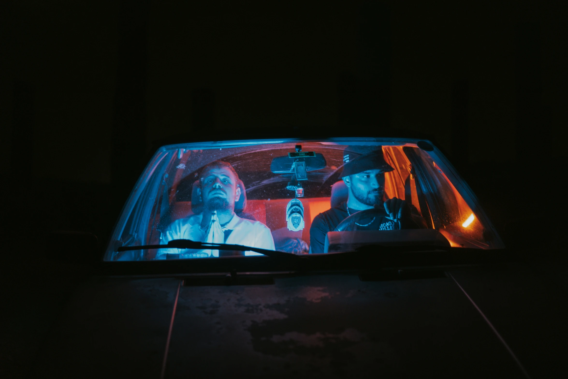 two people inside a car with an open laptop computer