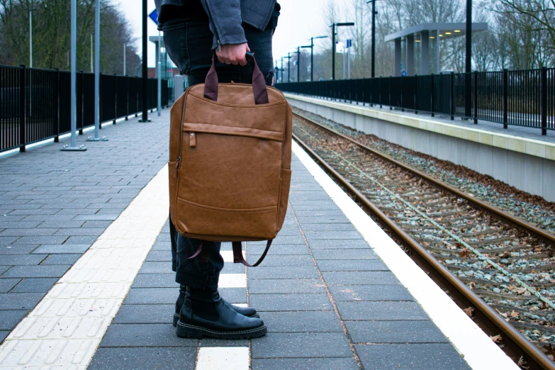 a man standing on train tracks with a bag in his hand