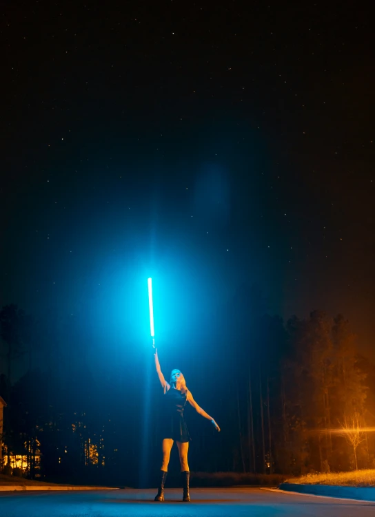 a person is holding up a blue light that is shining on the night sky