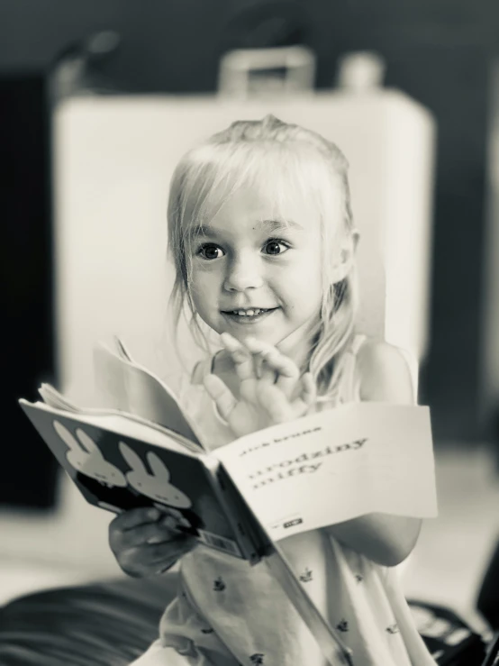 a young child smiling while reading a book