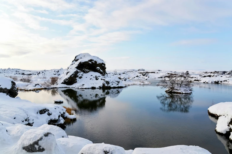 a lake surrounded by snow covered rocks under a blue sky