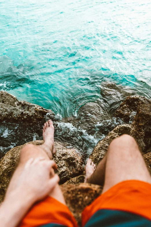 the legs of a person standing on a cliff overlooking the ocean