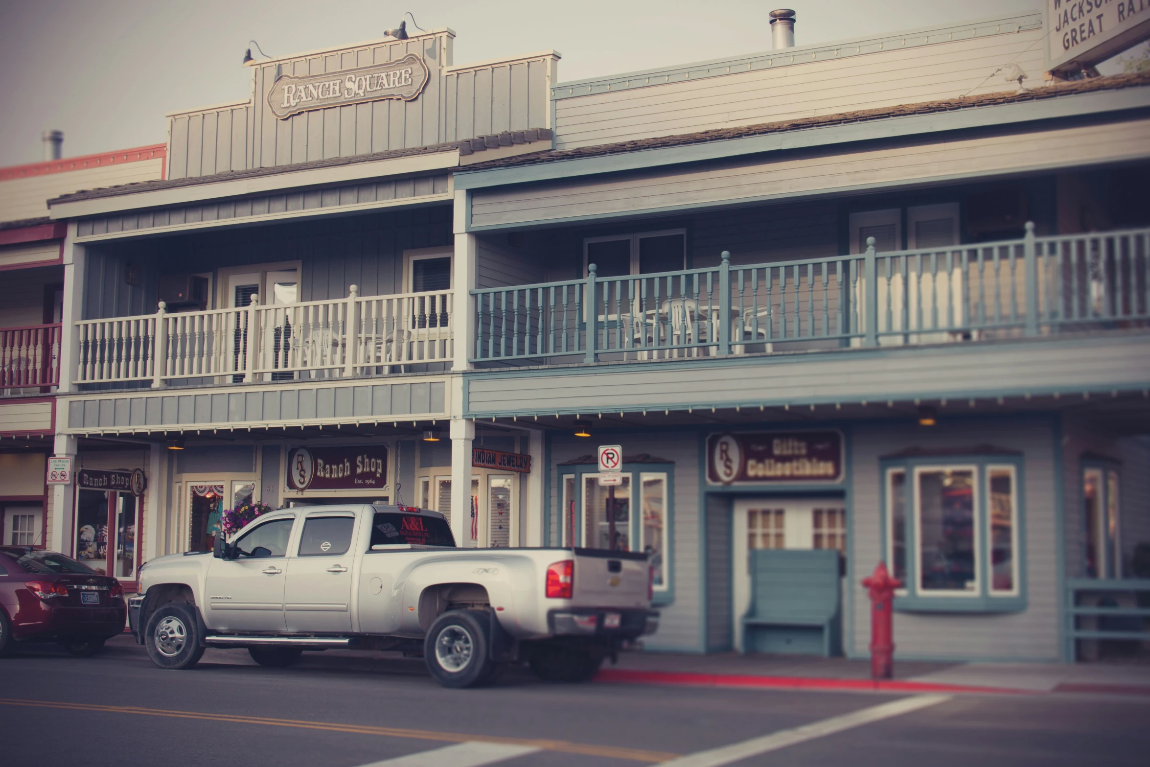 a car and truck are parked outside of some grey and white motels