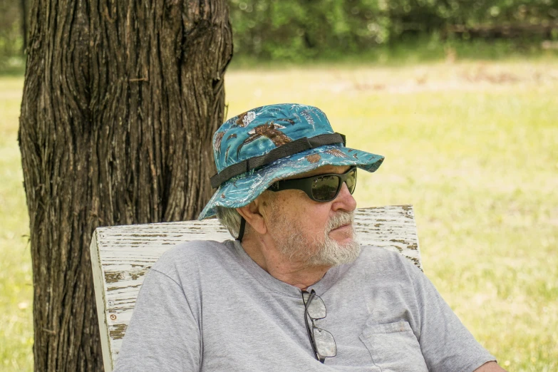 a man in a sun hat sitting down in the grass