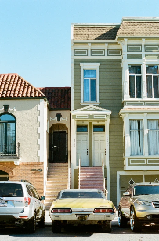 four cars parked in front of some older houses