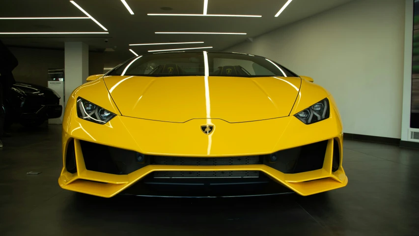 the front of a yellow sports car parked in a garage