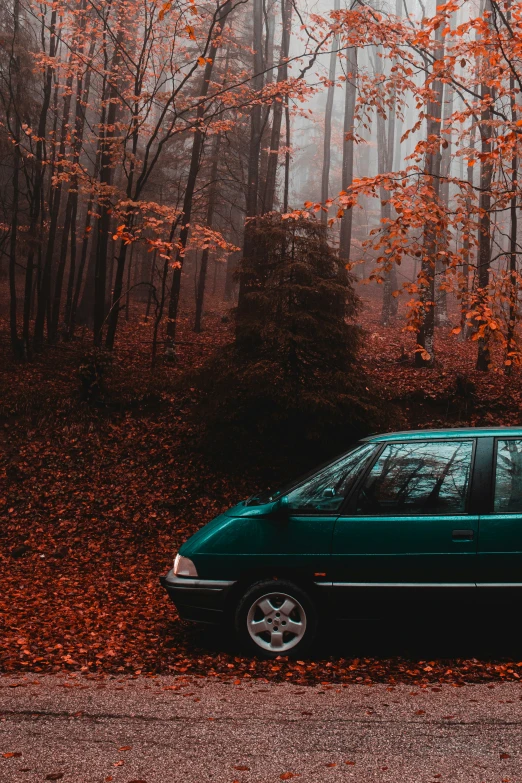 an emerald green car sits parked on the side of the road