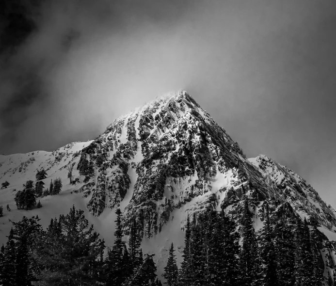 the top of a snow covered mountain under a cloudy sky