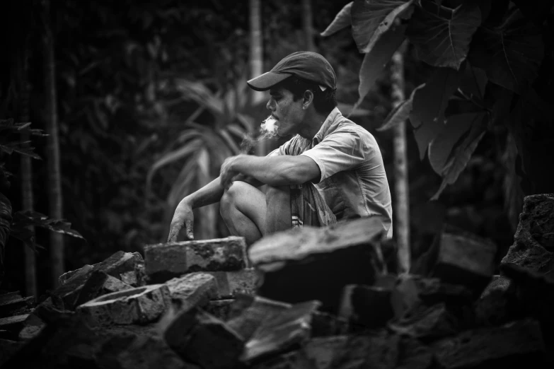 a man sitting on a rock surrounded by logs