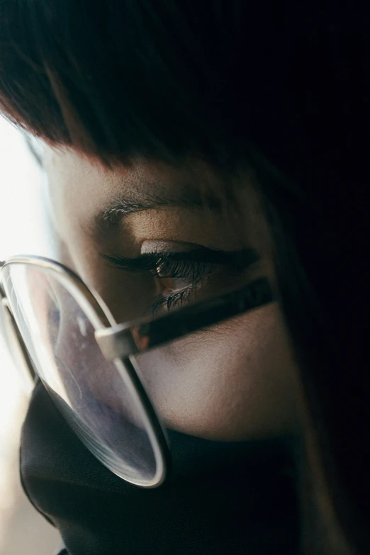 a close up of a person with eye glasses looking through a magnifying glass