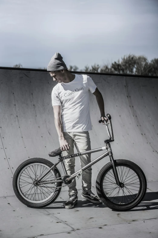 a man standing next to his bike in front of a wall