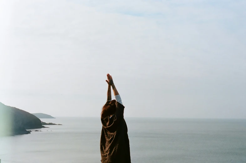 a woman stands with her hands up in the air