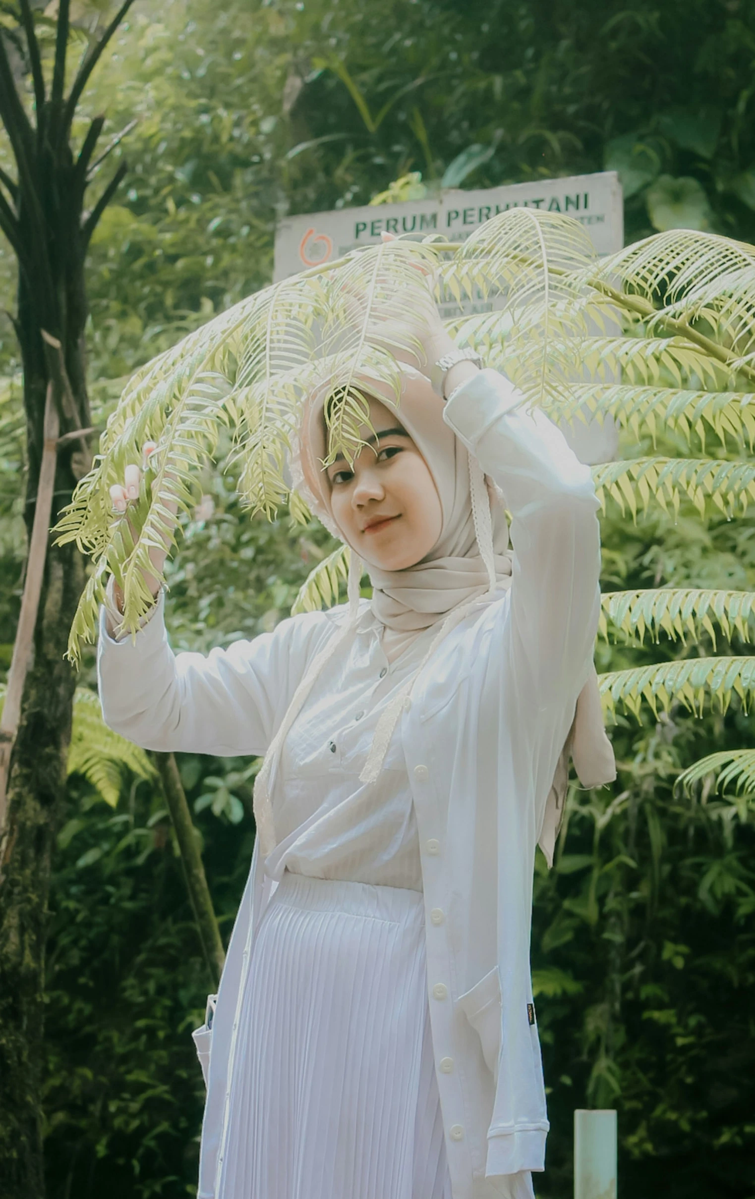 a woman with hijab holding up a plant