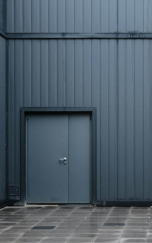 there is a grey door near a black building