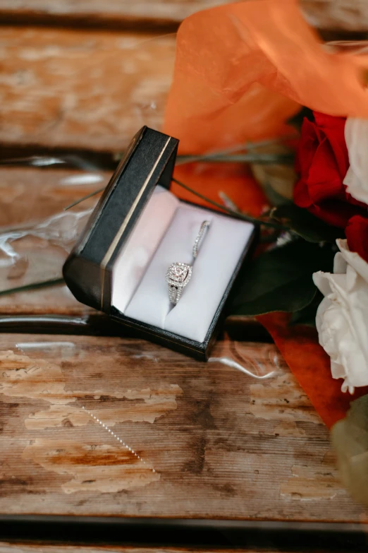 a brides ring and flower bouquet sitting on a wooden table