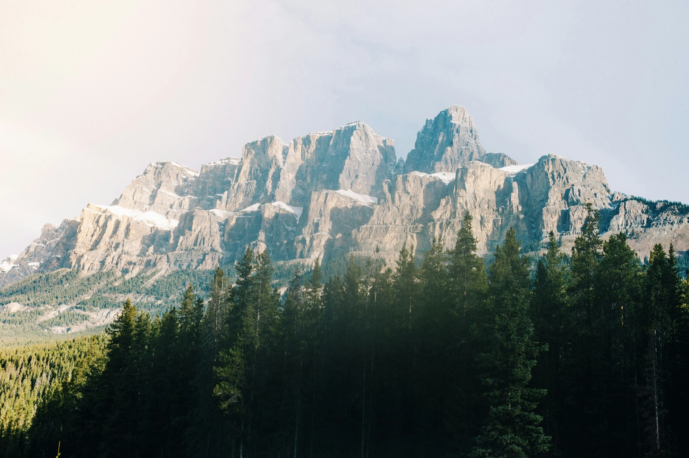 some people walking on the shore of a lake with large mountains in the background