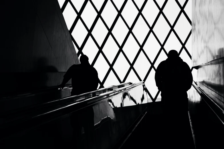 an image of two people on escalator looking through the railing