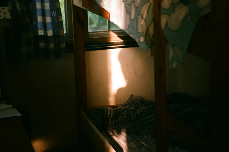 a bunk bed with the window showing sun streaming through