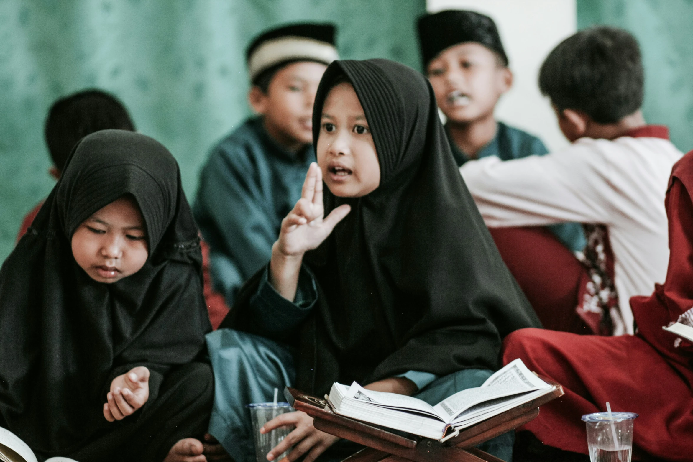 a group of muslim people sit down with books