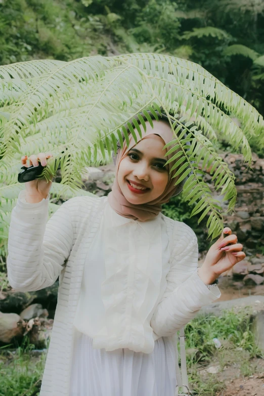 girl with headdress holding leaves, outdoors