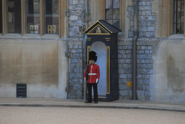 a british guard in uniform is standing outside the door to an old castle