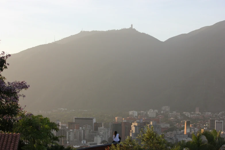 a person stands on top of a mountain looking down at the city