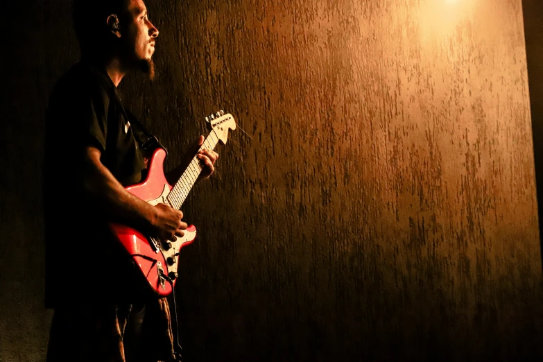 a man with an electric guitar in front of a dark wall