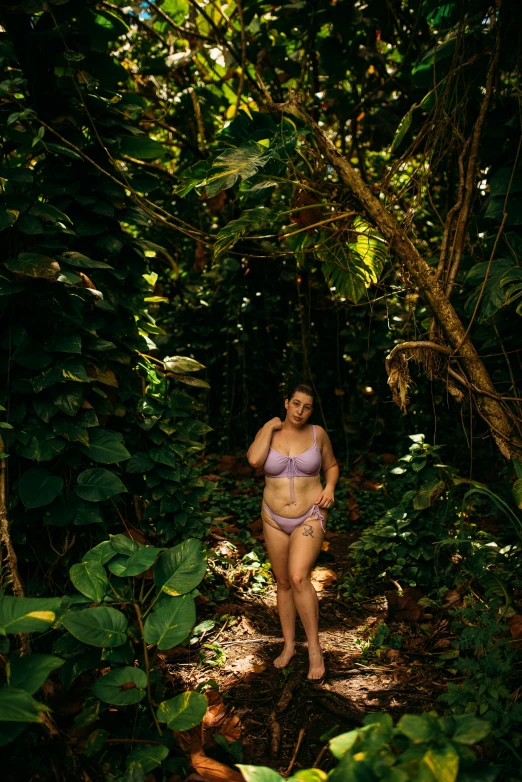 a pregnant woman in a bikini walks through the woods