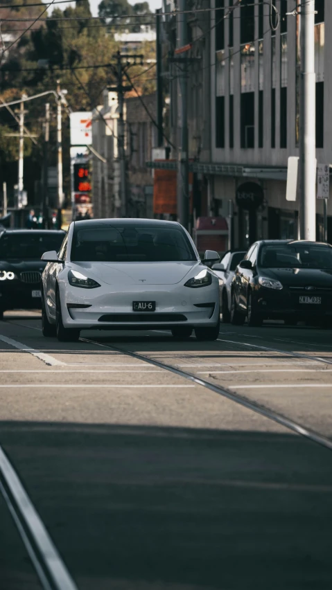a white car driving down a busy city street
